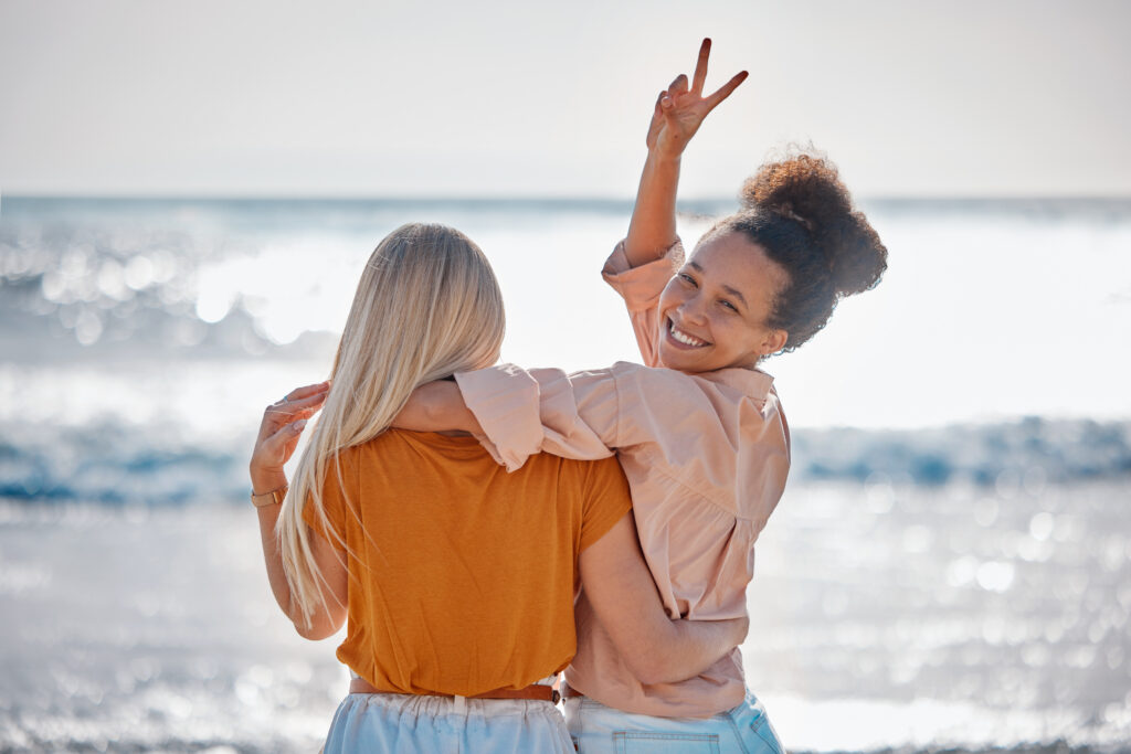 Hug, peace sign and portrait of friends at the beach