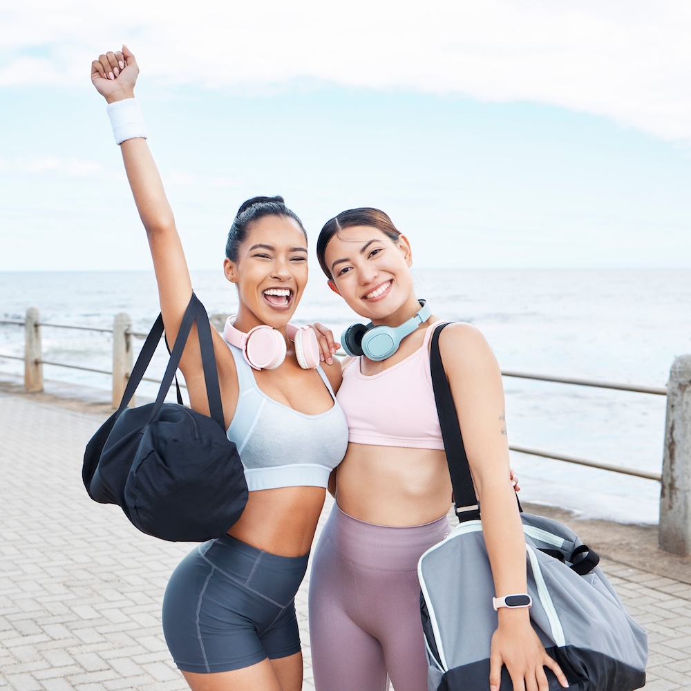 Excited, fitness friends exercise by ocean.