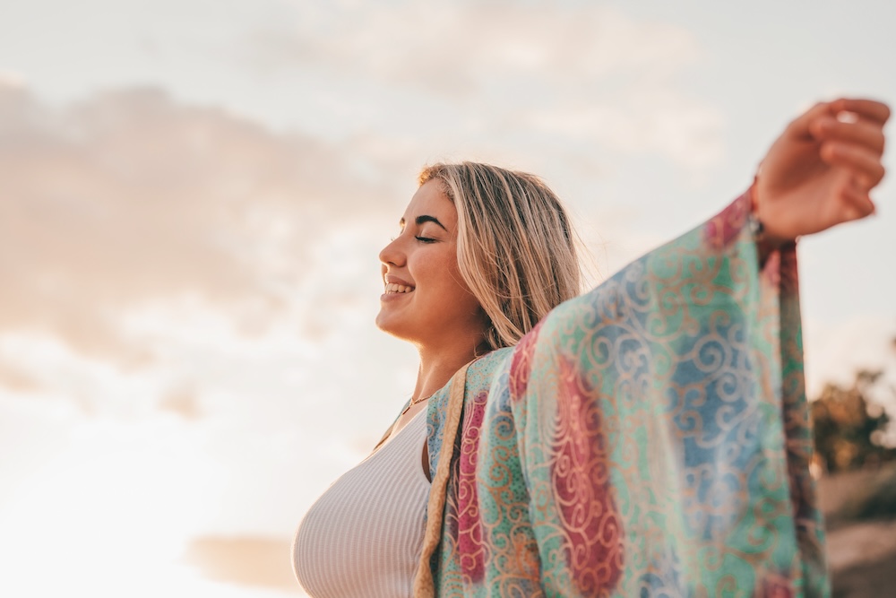 Portrait of one young woman at the beach with opened arm