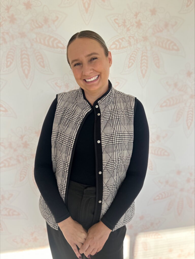 Team member photo of Corinne standing against Monima backdrop