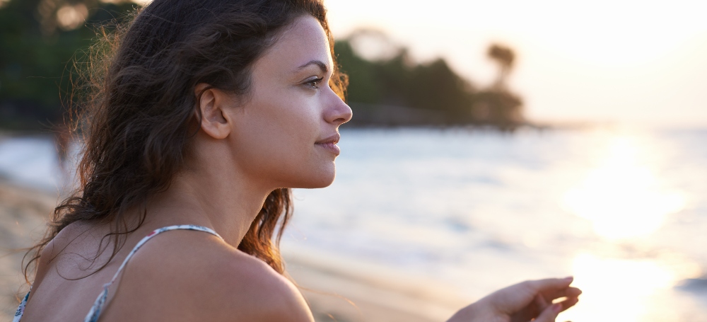 Woman looking out onto the beach at the sunset.