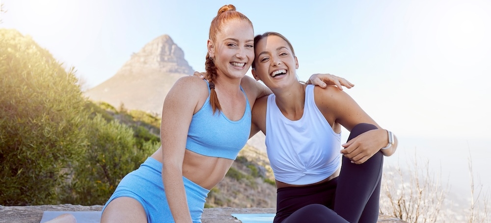 Girl friends smile after yoga with mountain in the background