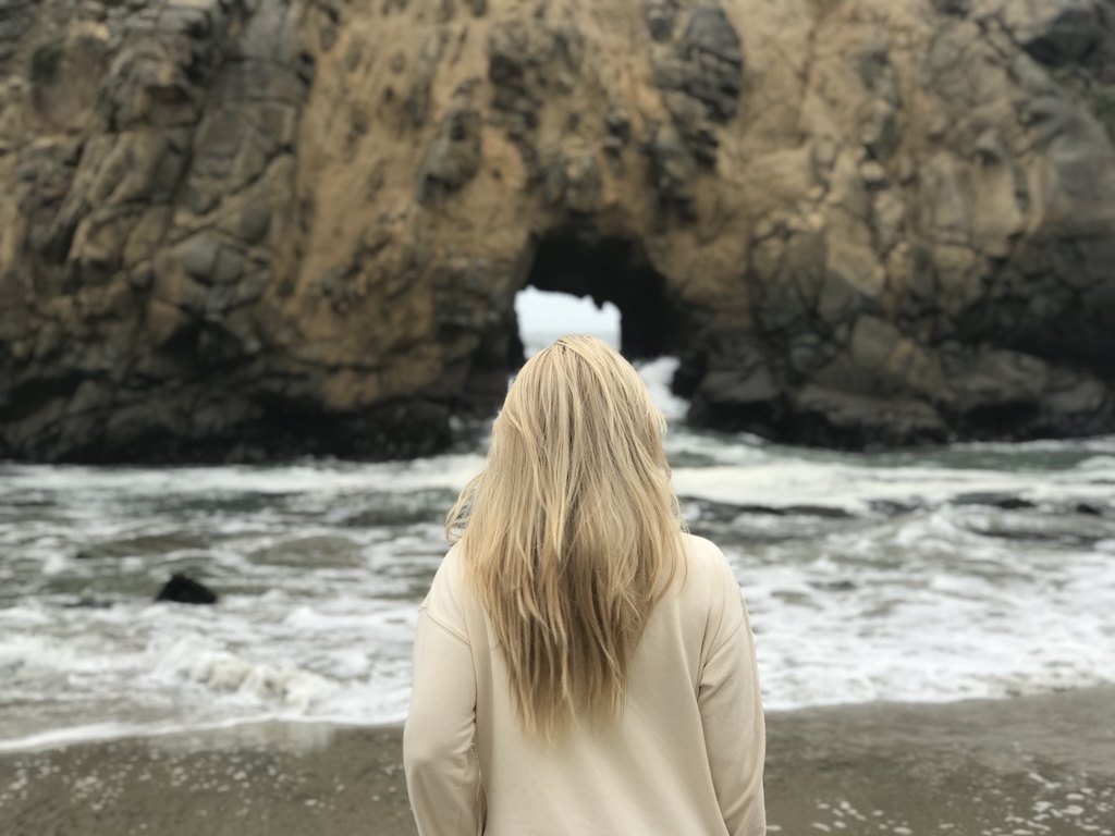 Woman looking thoughtfully out onto the water near the ocean at the beach.