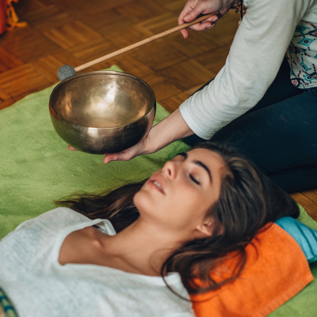 Tibetan singing bowl, woman laying down during sound healing session.