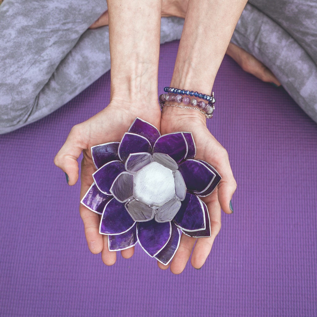 Top angle view of hands holding a purple glass lotus.