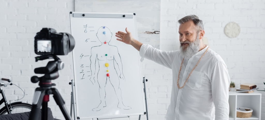 scientist and ayurvedic coach pointing at human chakras system, discussing the mind-body connection relevant in somatic therapy.