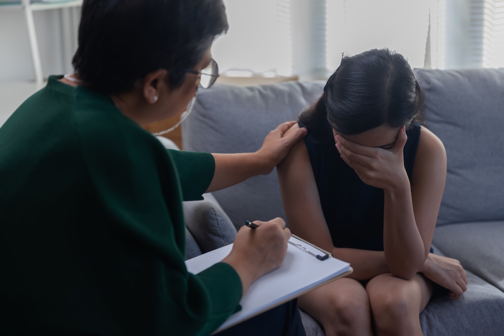 Young woman sitting with a psychiatrist, struggling with treatment resistant depression, seeking intensive support.