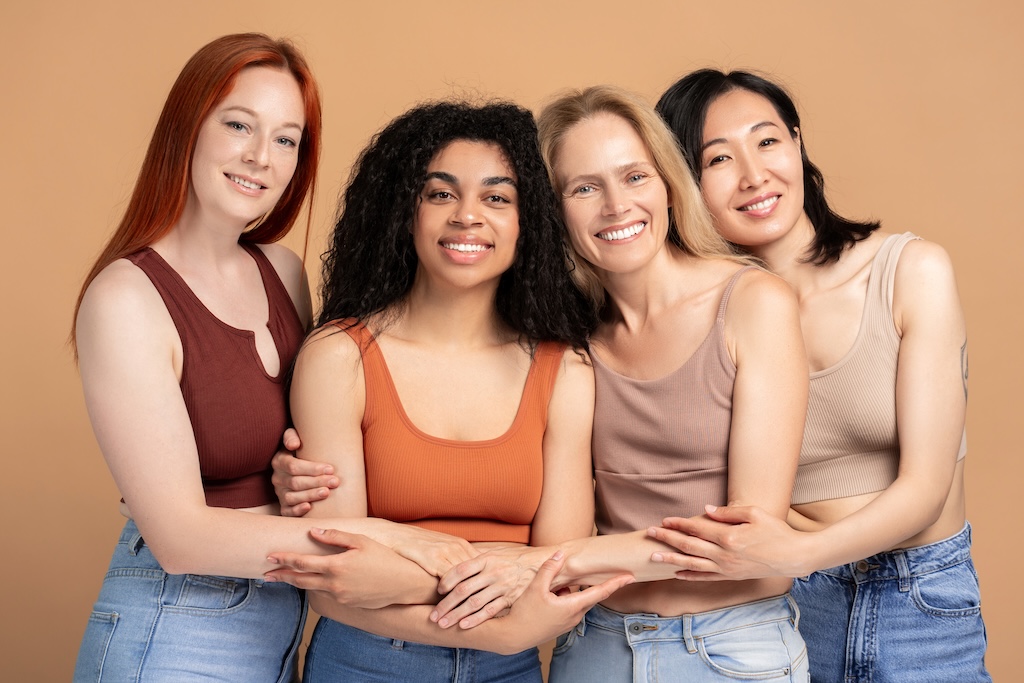 Four women are hugging each other, showcasing the power of female friendship and unity. They are all wearing casual clothing.